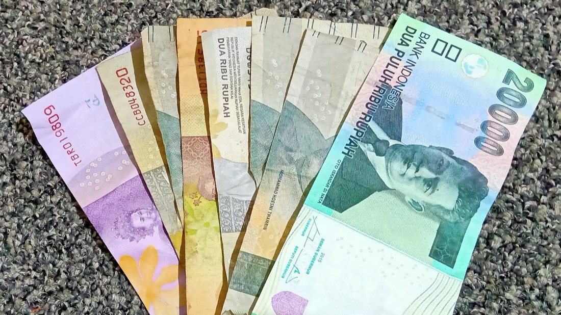 A fan of Indonesian rupiah banknotes in several denominations, a 20,000 note on top