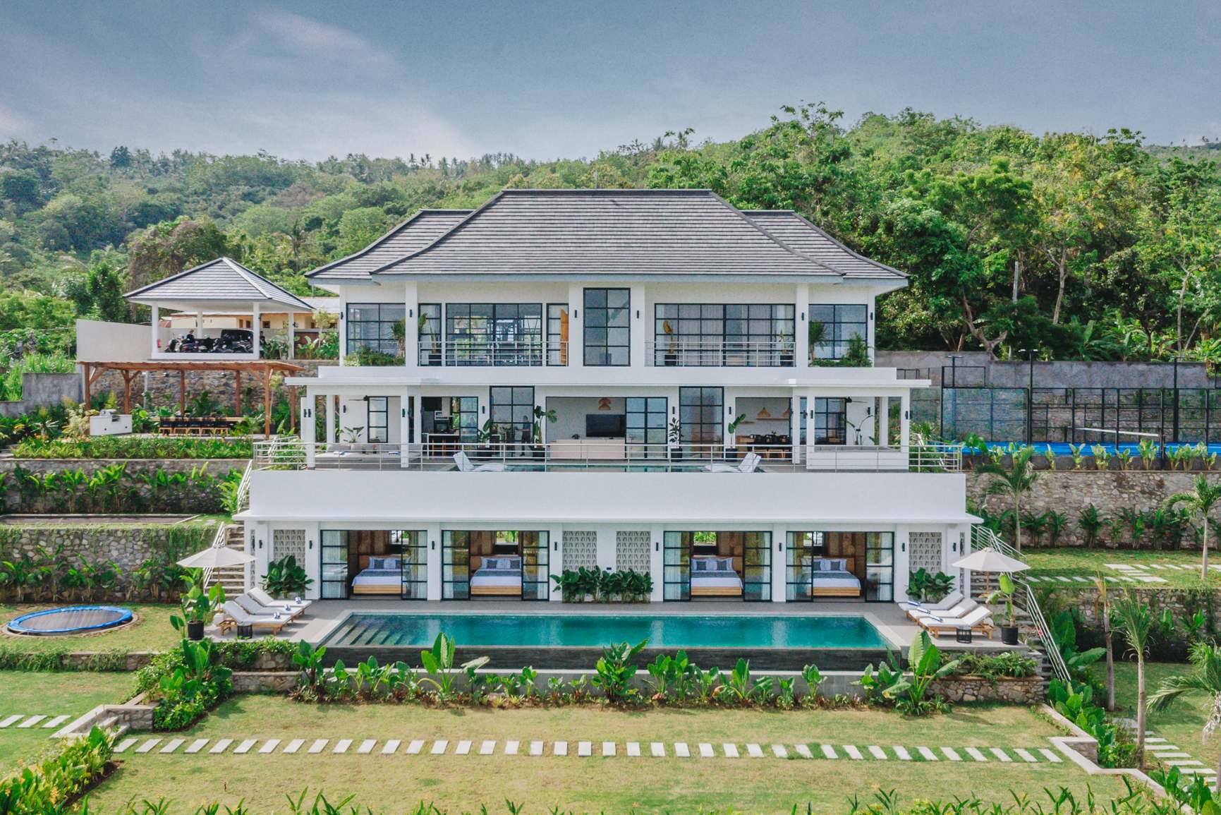 Villa Sunset from the air, a three-level Palm Living build with its pool, lawn and padel court in the hills above Lovina