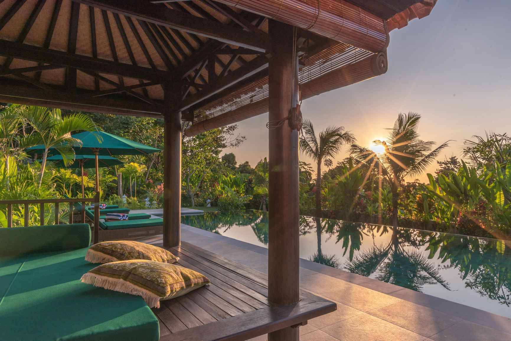 A daybed in the thatched gazebo beside the pool at Villa Mata Hari in low sun, in Selat above Lovina