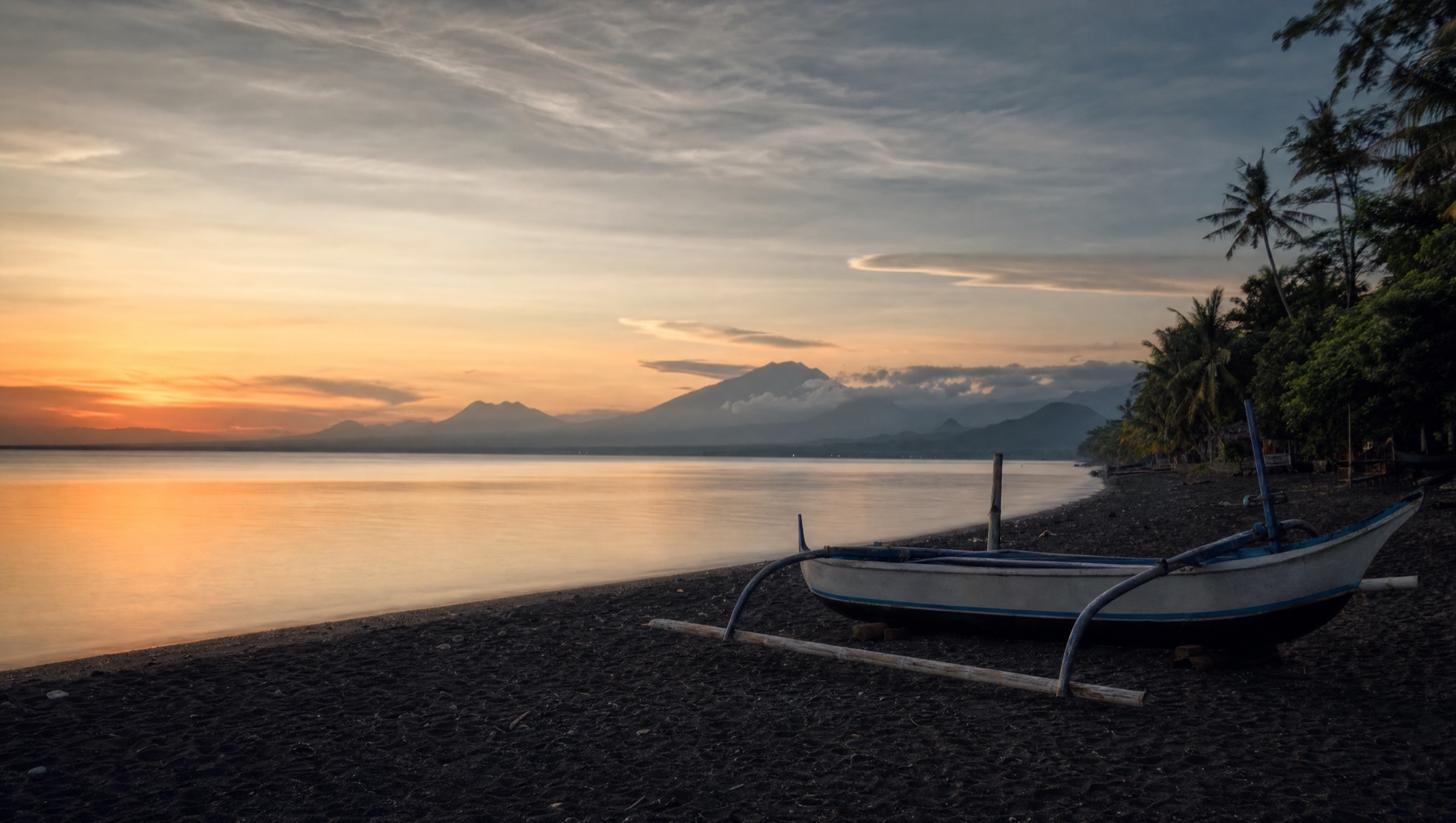 Calm black-sand Lovina Beach at sunset on Bali's north coast