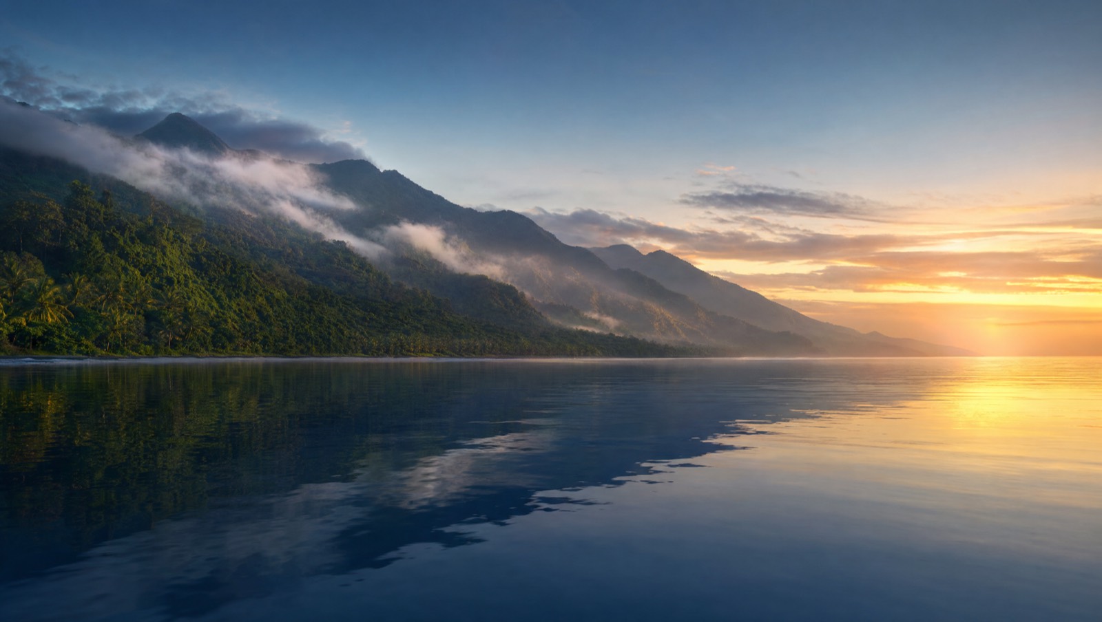 Breathtaking north Bali dawn with glassy sea and misty green hills