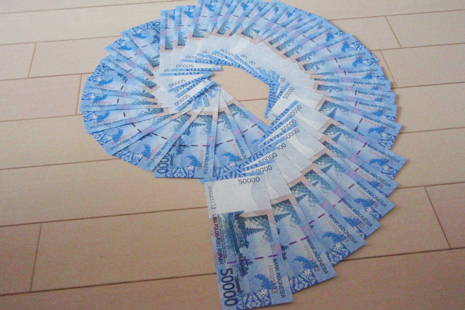 A spiral fan of blue 50,000 rupiah banknotes laid out on a wooden floor