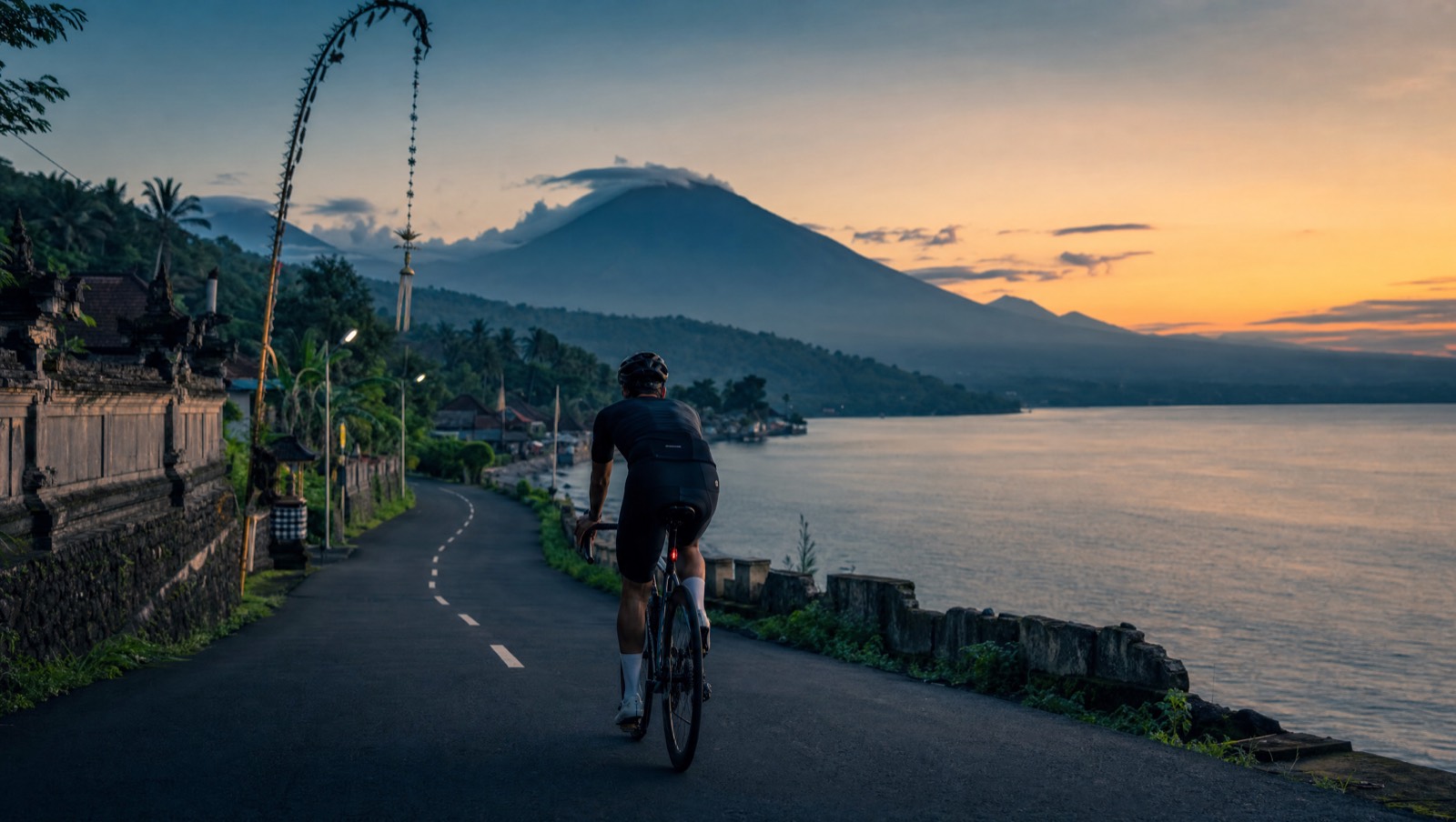 Road cyclist on a quiet north Bali coastal road at dawn