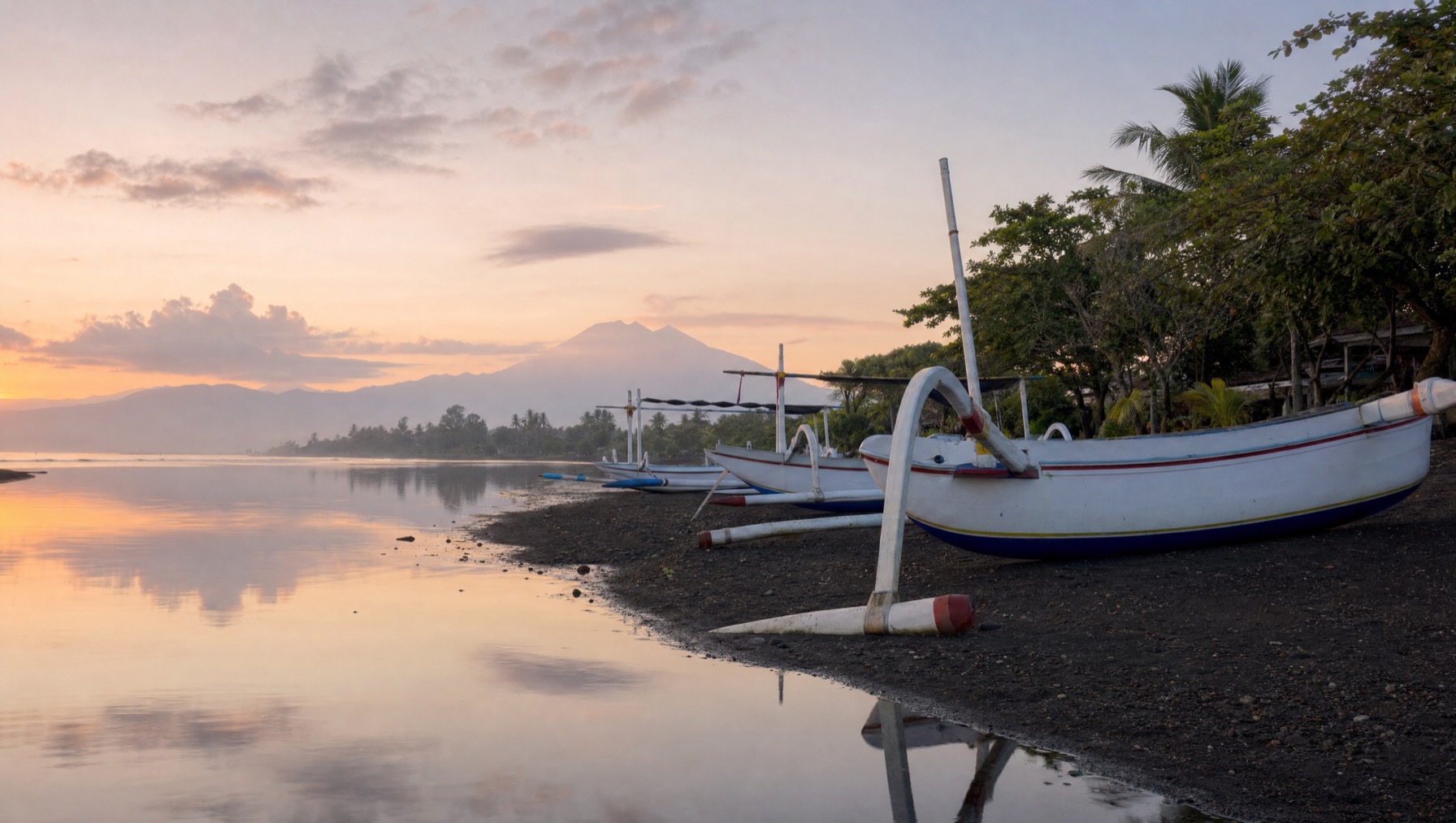 Traditional jukung outrigger boats on the calm black-sand beach at Lovina, north Bali, at dawn