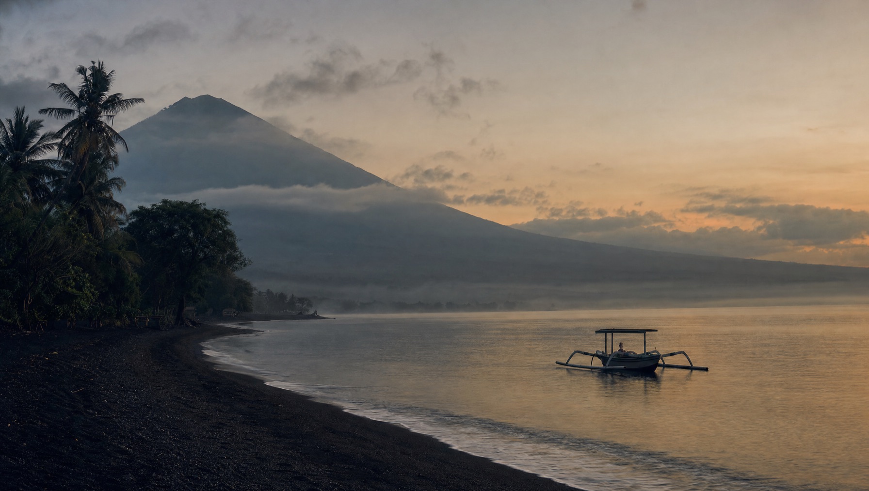 Quiet black-sand north Bali coast at dusk, an older and slower Bali